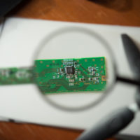 engineer-looking-circuit-board-through-magnifying-glass